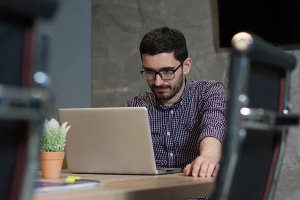 Genç işadamı ofiste onun laptop üzerinde çalışıyor