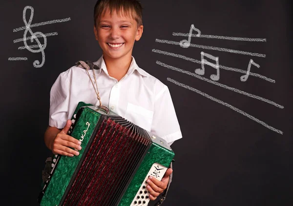 Akordeon, yazı tahtası üzerinde oynayan neşeli gülümseyen çocuk. Müzik konsepti
