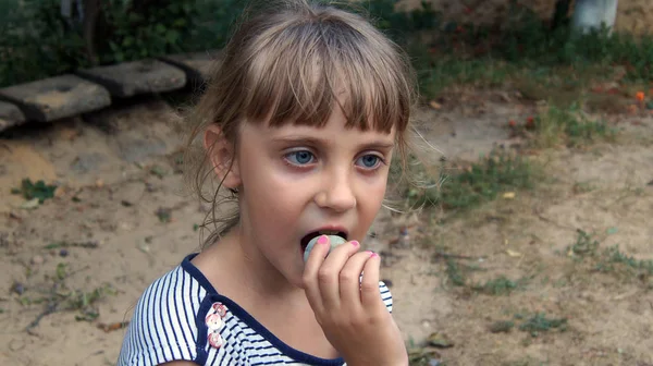 Kręcone happy mała dziewczynka jedzenie plum na zewnątrz. Koncepcja zdrowej żywności. — Zdjęcie stockowe