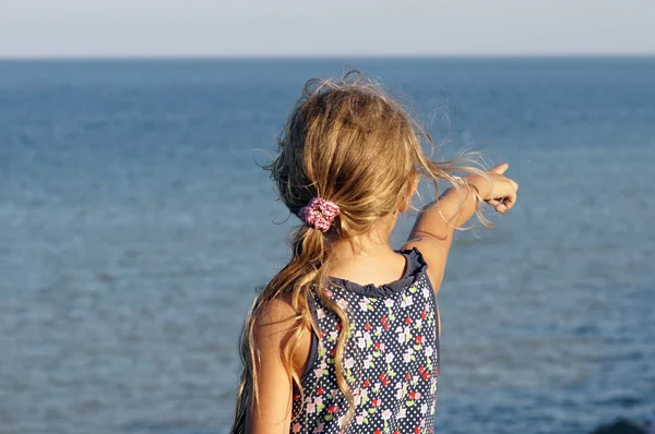 小女孩穿着彩色点她的手指在海 免版税图库照片