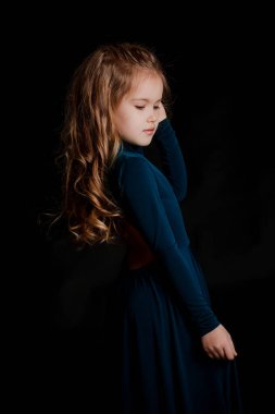 Siyah arka planda mavi elbiseli güzel sarışın kız.