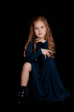 Siyah arka planda mavi elbiseli güzel sarışın kız.