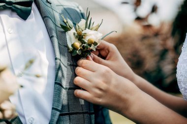 Gelinin eli damadın yaka çiçeğini tutar.