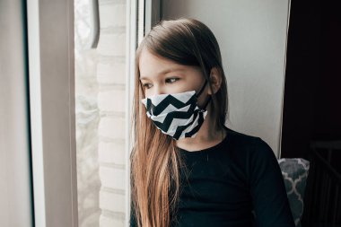 Siyah beyaz maskeli kız kendi kendini karantinaya aldı. Evin koronavirüsteki izolasyonu tüm dünyaya yayılmış ve yayılmış. Kentte sokağa çıkma yasağı olan kasvetli kadın sığınakta.