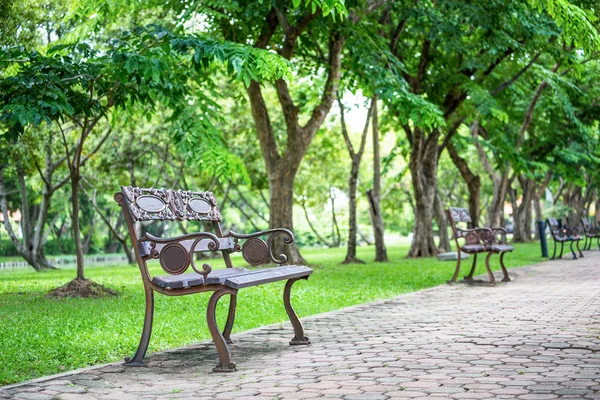 Assento de ferro vintage no caminho dentro do parque verde — Fotografia de Stock