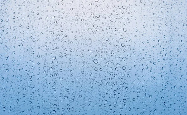 Выпускной голубой цвет капли дождевой воды на стекле — стоковое фото