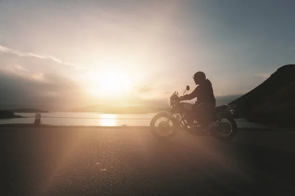 Silhouette of motorbike on road during sunset