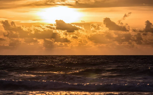 Темное море с золотым облачным небом заката — стоковое фото