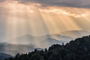 Turuncu güneş dağ için bulutlu gökyüzü parlıyor