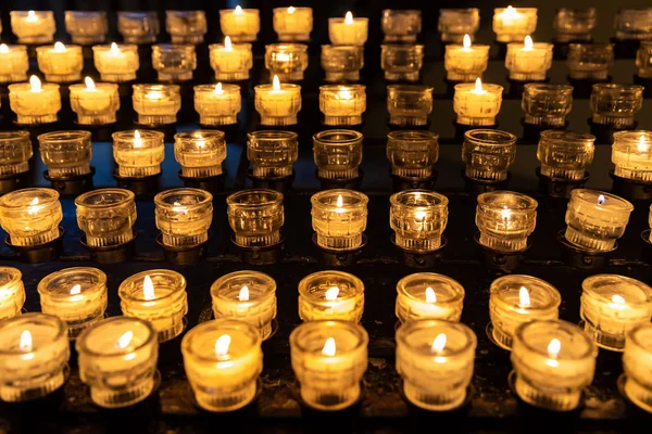 Cup of candle lighting on shelf in dark room Royalty Free Stock Photos