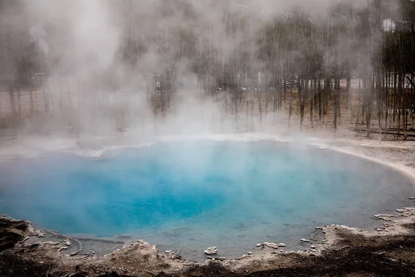 Blaues Geysirbecken mit kochendem Rauch in trockener Umgebung. — Stockfoto