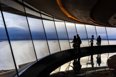 Seattle, Washington, USA - October 9, 2019: Silhouette scene of tourists looking down through big windows to see town of seattle from observation tower, Space Needle.