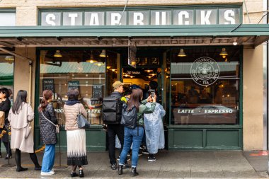 Seattle, Washington, USA - October 9, 2019: People waiting in long queue to get in first Starbucks shop of Pike Place Market.