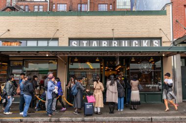 Seattle, Washington, USA - October 9, 2019: People waiting in long queue to get in first Starbucks shop of Pike Place Market.