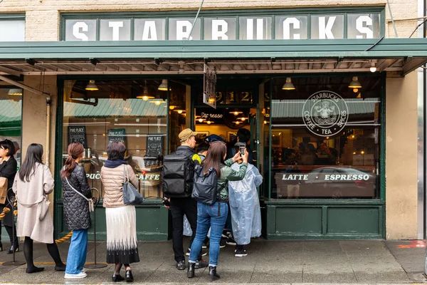 Seattle, Washington, USA - October 9, 2019: People waiting in long queue to get in first Starbucks shop of Pike Place Market.