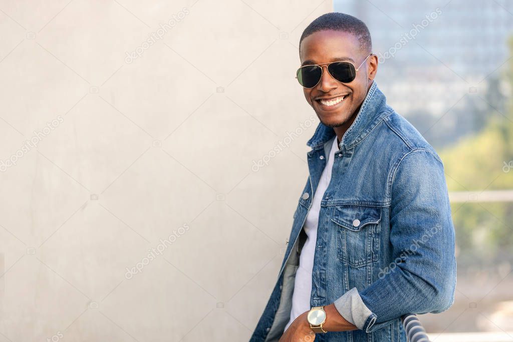 Cool hip stylish african american man in sun glasses and a jean jacket, lifestyle portrait on rooftop