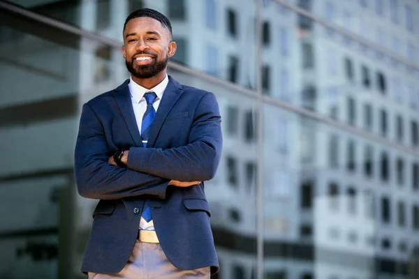 Lifestyle portrait of an african american business executive in a trendy suit and tie, cheerful, successful, proud, smiling near buildings