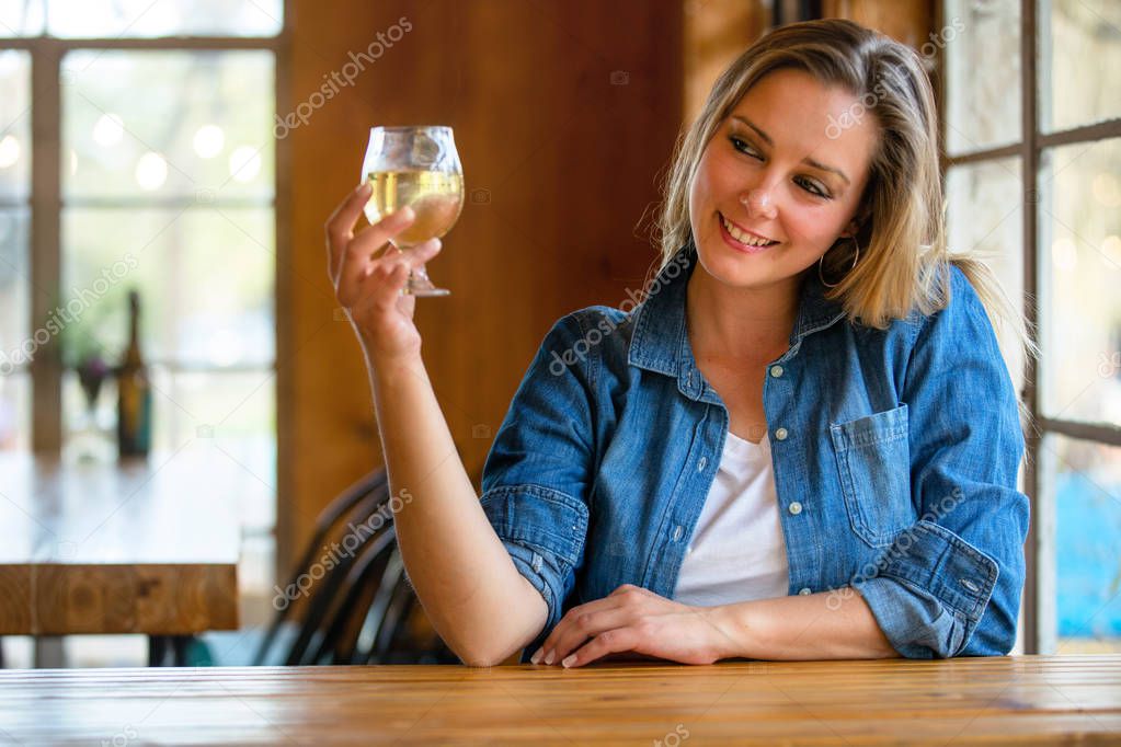 A woman drinking fresh craft cider from the tap, holding up her glass to cheers her friends at the bar