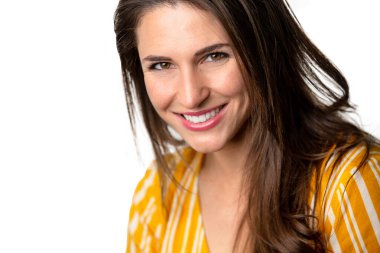 Sıcak, dost canlısı, neşeli, parlak gülümseyen genç esmer kadın beyaz arka planda soyutlanmış.