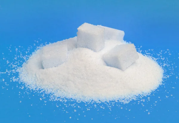 Pilha de açúcar branco isolada sobre fundo azul — Fotografia de Stock