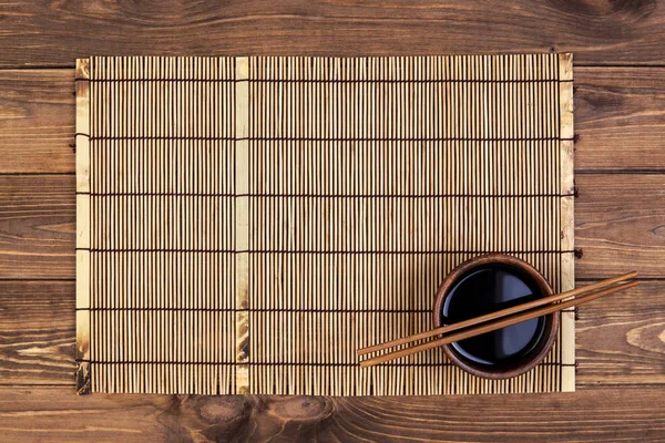 Tapete para sushi e pauzinhos em fundo de madeira. Vista superior com espaço de cópia — Fotografia de Stock
