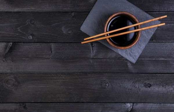 Antecedentes para sushi. Salsa de soja, palillos en piedra negra. Vista superior con espacio de copia — Foto de Stock