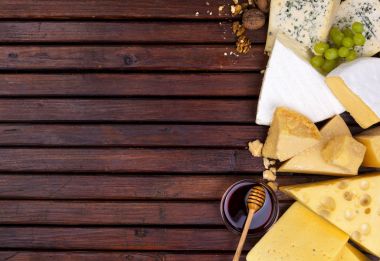 Boş alanı olan ahşap masa üzerinde çeşitli peynirler.