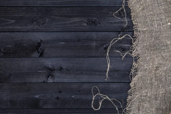 Mesa de madera negra con mantel de arpillera, vista superior, espacio para copiar — Foto de Stock