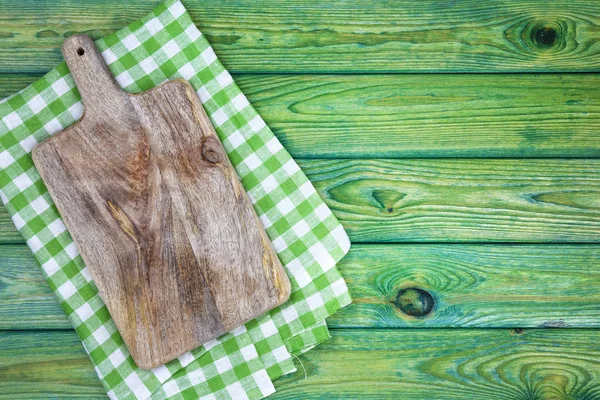 Tábua de corte sobre toalhas de mesa quadriculadas verdes na mesa, vista superior — Fotografia de Stock
