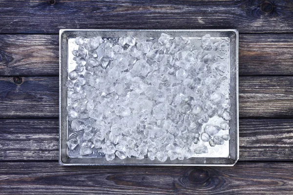 Hielo triturado en bandeja sobre fondo de madera oscura. Copiar espacio, vista superior — Foto de Stock