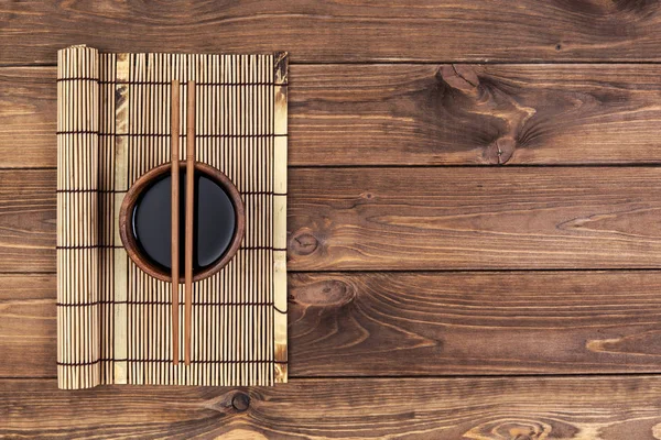 Tapete para sushi e pauzinhos em fundo de madeira . — Fotografia de Stock