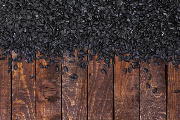 Black sunflower seeds on wooden background, top view, copy space — Stock Photo, Image