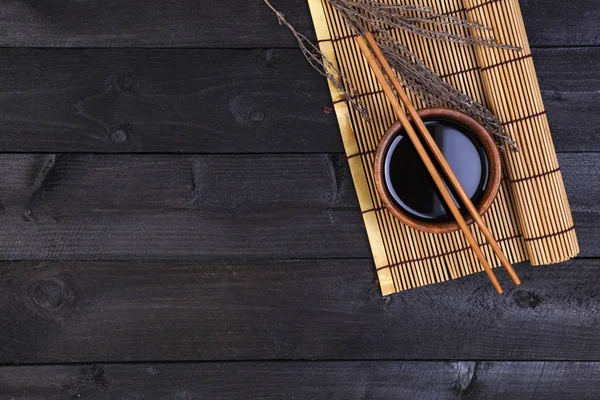 Bambumatta och sojasås på mörkt träbord. Ovanifrån — Stockfoto
