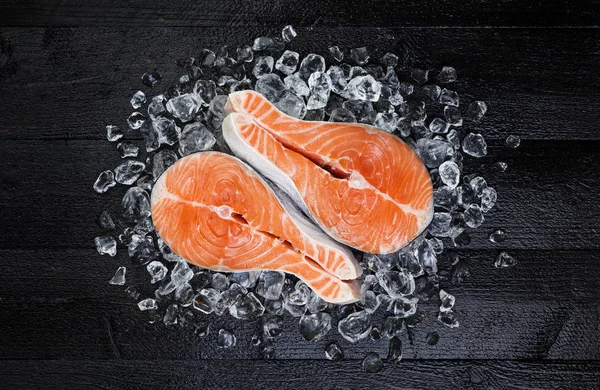 Filete de salmón sobre hielo sobre mesa de madera negra vista superior — Foto de Stock