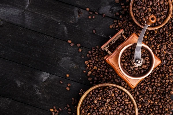 Fondo café, vista superior con espacio para copiar. Café molido, molino de café, tazón de granos de café tostados sobre fondo de madera negro —  Fotos de Stock