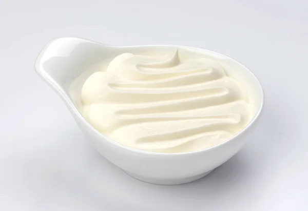 Iogurte grego em tigela sobre fundo branco, creme isolado — Fotografia de Stock