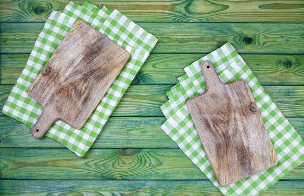 Placa de corte sobre toalha de mesa quadriculada verde, vista superior — Fotografia de Stock