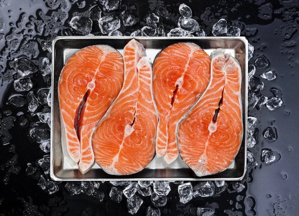 Filetes de salmón sobre hielo sobre fondo negro — Foto de Stock
