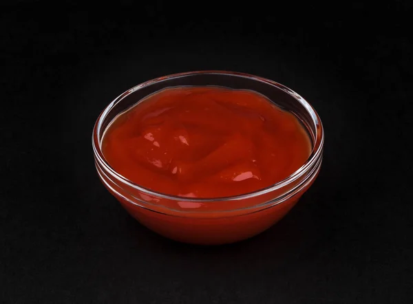 Ketchup dans un bol sur fond noir — Photo