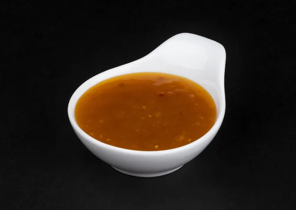 Сладкий и кислый соус в белой миске изолирован на черном фоне — стоковое фото