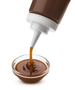 Pouring caramel sauce with bottle isolated on white background
