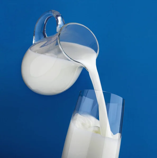 푸른 배경에 분리 된 유리 속에서 우유를 끓이는 모습 — 스톡 사진