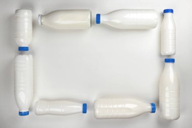 Beyaz arka planda süt ve yoğurt için şişelerden yapılmış çerçeve, üst manzara