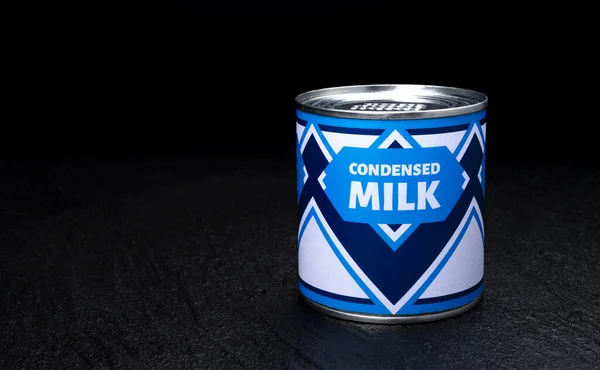 Kondenserad mjölk burk på svart bakgrund — Stockfoto