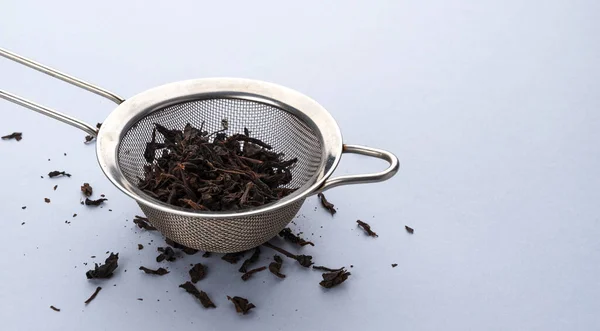 Colador de té con hojas secas de té negro y espacio de copia para texto — Foto de Stock
