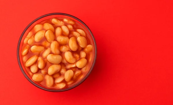 Feijão assado em molho de tomate isolado no fundo vermelho — Fotografia de Stock