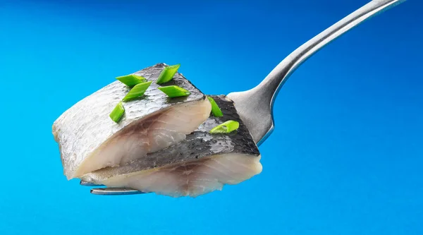 蓝色背景隔离的叉子上的咸鲱鱼片 — 图库照片