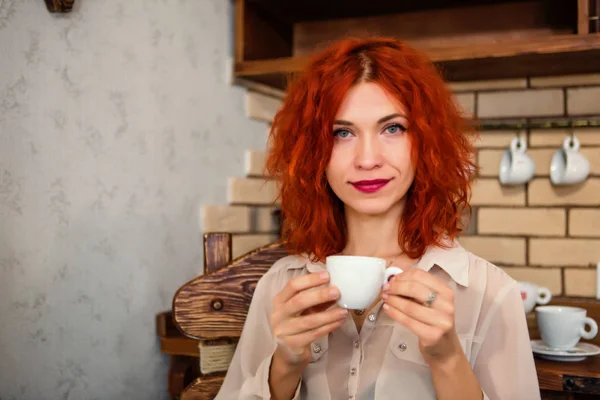 Hermosa chica con el pelo rojo está sosteniendo una taza de espresso en su — Foto de Stock