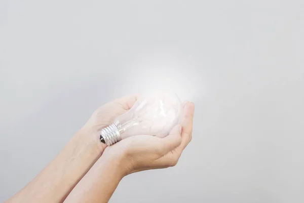 La mano de la mujer sostiene una bombilla eléctrica incandescente que brilla. Cr. —  Fotos de Stock