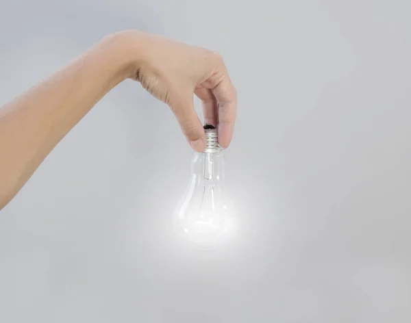 La main de la femme tient une ampoule électrique incandescente qui brille. Cr — Photo